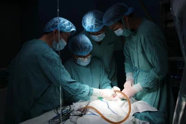 Các bác sỹ đang thực hiện ca phẫu thuật cho cháu bé. (Ảnh: Hồ Cầu/TTXVN)