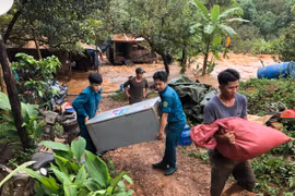 Lực lượng dân quân hỗ trợ người dân di dời tài sản ra khỏi vùng lũ. (Ảnh: Đậu Tất Thành/TTXVN)