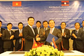 Bộ trưởng Bộ Thông tin và Truyền thông Nguyễn Mạnh Hùng (trái) và Bộ trưởng Bộ Thông tin, Văn hóa và Du lịch Lào Bosengkham Vongdala (phải) trao biên bản hợp tác đã ký kết. (Ảnh: Xuân Tú/TTXVN) 