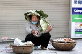 Người lao động dùng đủ mọi cách để chống chọi với nắng nóng gay gắt ngoài đường lên đến hơn 40 độ C. (Ảnh: Thành Đạt/TTXVN)