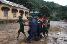 Lực lượng cứu hộ đưa em Nguyễn Minh Lâm bị đa chấn thương từ bản Sa Ná ra ngoài để chữa trị. (Ảnh: TTXVN)