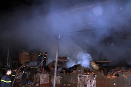 Lực lượng Cảnh sát Phòng cháy chữa cháy nỗ lực phun nước dập tắt đám cháy. (Ảnh: Ngọc Minh/TTXVN)