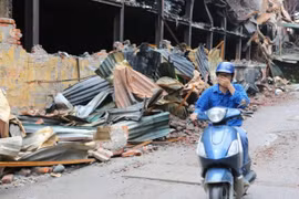 Người dân sinh sống tại đây phải đeo khẩu trang mỗi khi đi qua khu vực cháy nhà máy Bóng đèn Phích nước Rạng Đông. (Ảnh: Thành Đạt/TTXVN)