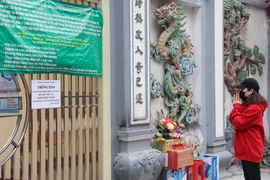 Người dân nghiêm túc thực hiện quy định không tụ tập tại các địa điểm đông đúc mà chỉ đứng từ xa vái vọng. (Ảnh: Hoài Nam/Vietnam+)