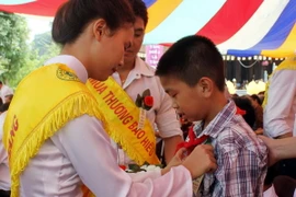  Nghi lễ cài hoa hồng lên ngực áo cho các em học sinh. (Ảnh: Lan Anh/TTXVN) 