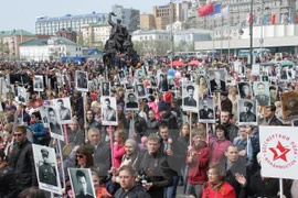 Người dân Nga mang ảnh người thân hy sinh trong Chiến tranh Thế giới thứ II tại lễ kỷ niệm 70 năm Ngày Chiến thắng ở thành phố Vladivostok ngày 9/5. (Nguồn: THX/TTXVN) 