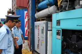 Lực lượng chức năng mở kiểm tra các container hàng nhập lậu tại khu vực Cảng Hiệp Phước. (Ảnh: Mạnh Linh/TTXVN) 