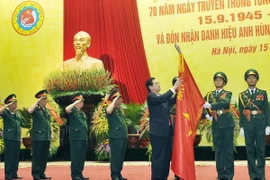 Thủ tướng Nguyễn Tấn Dũng gắn Huy hiệu Anh hùng lực lượng vũ trang nhân dân lên Cờ truyền thống của Tổng cục Công nghiệp Quốc phòng. (Ảnh: Trọng Đức/TTXVN) 