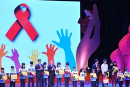 Trao sổ tiết kiệm cho các em học sinh nhiễm HIV có hoàn cảnh đặc biệt khó khăn. (Ảnh: Minh Đức/TTXVN) 