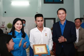 Đại diện Trung ương Đoàn trao Huy hiệu Tuổi trẻ dũng cảm tặng anh Nguyễn Ngọc Mạnh. (Ảnh: TTXVN phát)