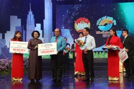 Chủ tịch Ủy ban MTTQ Việt Nam Thành phố Hồ Chí Minh Tô Thị Bích Châu tiếp nhận tượng trưng số tiền ủng hộ từ các nhà hảo tâm. (Ảnh: Xuân Khu/TTXVN)