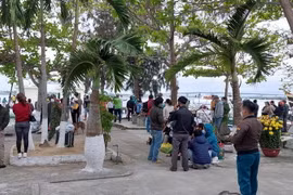 Người dân theo dõi lực lượng chức năng tìm kiếm nạn nhân mất tích tại Cửa Đại. (Ảnh: TTXVN)
