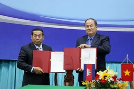 Chủ tịch Ủy ban Nhân dân tỉnh An Giang Nguyễn Thanh Bình (phải ) và ngài Ouch Phea, Tỉnh trưởng tỉnh Takeo (Vương quốc Campuchia) ký thỏa thuận hợp tác giữa hai tỉnh trong thời gian tới. (Ảnh: Công Mạo/TTXVN)