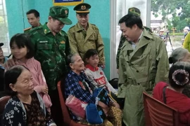 Chủ tịch UBND thành phố Tam Kỳ Bùi Ngọc Ảnh (mặc áo mưa bên phải) động viên người dân vùng trũng thấp xã ven biển thành phố về nơi ở an toàn trước khi bão vào đất liền. (Ảnh : Đoàn Hữu Trung/TTXVN)