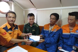 Đại diện Trung tâm Phối hợp tìm kiếm, cứu nạn hàng hải Việt Nam trao quà hỗ trợ cho các thuyền viên tàu cá Bình Định sau khi được cứu nạn trên biển. (Ảnh: Phan Sáu/TTXVN)