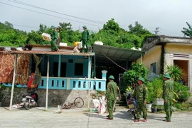 Cán bộ chiến sỹ Đồn biên phòng Cù Lao Chàm, bộ đội biên phòng Quảng Nam giúp đỡ người dân gia cố mái nhà bằng bao tải cát. (Ảnh: Đoàn Hữu Trung/TTXVN)