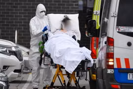 Nhân viên y tế chuyển bệnh nhân COVID-19 lên xe cứu thương tại thành phố Melbourne, Australia. (Ảnh: AFP/TTXVN)