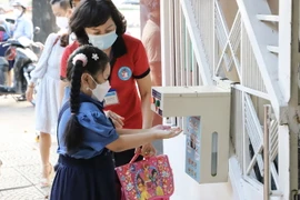 Học sinh trường tiểu học Hòa Bình, quận 1, được giáo viên hướng dẫn rửa tay trước khi vào lớp. (Ảnh: Hồng Giang/TTXVN)