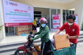 Nhân viên Hội Chữ thập đỏ hỗ trợ người dân vận chuyển nhu yếu phẩm về nhà. (Ảnh: Trần Lê Lâm/TTXVN) 
