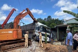 Lực lượng chức năng sử dụng xe chuyên dụng cẩu xe tải, khắc phục hậu quả vụ tai nạn. (Ảnh: TTXVN phát)