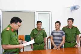 Đại diện Cơ quan Cảnh sát điều tra Công an tỉnh thi hành lệnh bắt tạm giam Nguyễn Văn Cuộc. (Ảnh: TTXVN phát)