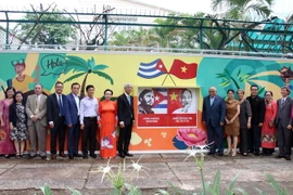 Các đại biểu chụp hình lưu niệm bên bức tranh vẽ cổ động về tình hữu nghị nhân dân Việt Nam-Cuba. (Ảnh: Tiến Lực/TTXVN)
