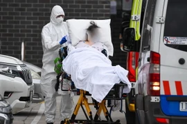 Nhân viên y tế chuyển bệnh nhân COVID-19 lên xe cứu thương tại thành phố Melbourne, Australia. (Ảnh: AFP/TTXVN)