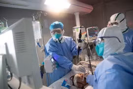 Nhân viên y tế điều trị cho bệnh nhân COVID-19 tại bệnh viện. (Ảnh: AFP/TTXVN)