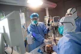 Nhân viên y tế điều trị cho bệnh nhân COVID-19 tại bệnh viện. (Ảnh: AFP/TTXVN)