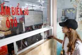 Người dân đến đăng ký và thực hiện bấm nút lấy biển số xe ôtô. (Ảnh: TTXVN phát)