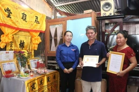 Quyền Bí thư Tỉnh đoàn Vĩnh Long Nguyễn Thụy Yến Phương trao Huy hiệu “Tuổi trẻ dũng cảm” cho gia đình em Nguyễn Minh Quân. (Ảnh: Lê Thúy Hằng/TTXVN)