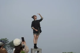 Du khách thích thú chụp ảnh với khoảnh khắc mây trôi lơ lửng trên mặt đất. (Ảnh: Phan Sáu/TTXVN)