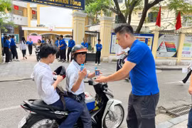 Tình nguyện viên hỗ trợ nước uống cho sỹ tử, phụ huynh tại điểm thi trường Trung học phổ thông Trần Nhân Tông. (Ảnh: PV/Vietnam+)