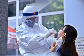 Nhân viên y tế lấy mẫu dịch hầu họng để xét nghiệm bằng phương pháp RT-PCR cho người dân trở về từ Đà Nẵng tại Nhà Hộ Sinh B - Trung Tâm Y Tế Quận Hai Bà Trưng. (Ảnh: Minh Quyết/TTXVN)