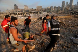 Chuyển người bị thương tại hiện trường đổ nát sau vụ nổ kinh hoàng ở khu cảng thủ đô Beirut, Liban. (Ảnh: AFP/TTXVN)