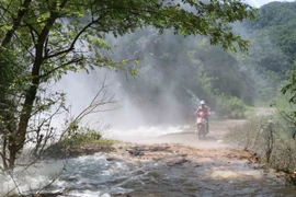 Người dân gặp khó khăn khi đi qua những điểm xuất hiện dòng thác lũ đổ xuống từ vách núi bên đường. (Ảnh: Xuân Tiến/TTXVN)