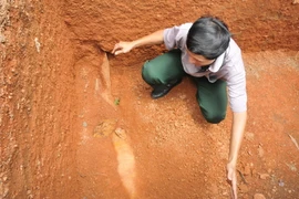 Anh Khoa với quả bom phát hiện khi đào bể xử lý nước thải.(Ảnh: Đậu Tất Thành/TTXVN)