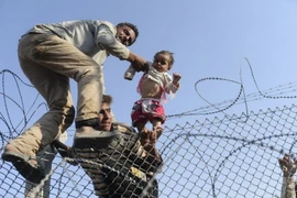 Người di cư Syria cố vượt qua hàng rào dây thép gai để vào lãnh thổ Thổ Nhĩ Kỳ. (Nguồn: AFP/TTXVN)