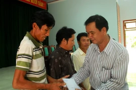Trao tiền hỗ trợ cho các ngư dân. (Ảnh: Sỹ Thắng/TTXVN)