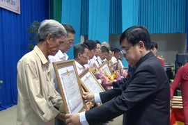 Chủ tịch UBND tỉnh Long An Đỗ Hữu Lâm trao danh hiệu Bà mẹ Việt Nam Anh hùng cho các thân nhân Mẹ Việt Nam Anh hùng năm 2014. (Ảnh: Thanh Bình/TTXVN)