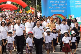 Lãnh đạo Chính phủ và các Bộ, ban ngành đi bộ kêu gọi toàn dân đội mũ bảo hiểm cho trẻ em khi tham giao giao thông. (Ảnh: Việt Hùng/Vietnam+)