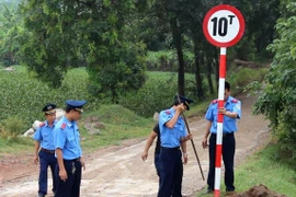 Thanh tra giao thông huyện Đông Anh cắm biển tải trọng để kiểm soát xe chở vật liệu xây dựng đi vào bãi đổ thải ven đê sông Hồng. (Ảnh: MM/Vietnam+)