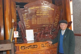 Ông Nguyễn Trọng Phùng bên bảng vàng lưu danh gia tộc lương y. (Ảnh: Hùng Võ/Vietnam+)