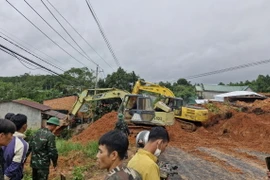 Lực lượng chức năng cùng thiết bị cơ giới triển khai công tác cứu hộ, giải tỏa hiện trường vụ sạt lở. (Ảnh: TTXVN phát)