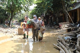 Người dân vẫn phải lội bùn khi di chuyển trên 2 tuyến phố Thanh Niên và Trần Hưng Đạo, Yên Bái, chiều 14/9. (Ảnh: Tuấn Anh/TTXVN)