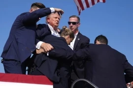 Cựu Tổng thống Donald Trump được mật vụ Mỹ hộ tống rời khỏi bục diễn thuyết trong cuộc vận động tranh cử ở thành phố Butler, bang Pennsylvania sau khi xảy ra vụ nổ súng, ngày 13/7. (Ảnh: THX/TTXVN')