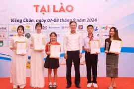 Đại biện lâm thời Đại sứ quán Việt Nam tại Lào Phan Minh Chiến trao phần thưởng cho các thí sinh đạt giải Lễ Tôn vinh tiếng Việt tại Lào năm 2024. (Ảnh: Xuân Tú/TTXVN)