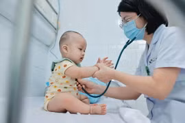 Bác sỹ khám cho bệnh nhi điều trị bệnh tay chân miệng. (Ảnh: Minh Quyết/TTXVN)