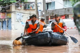 Cảnh sát Trung Quốc giúp sơ tán người dân khỏi các khu vực ngập lụt. (Ảnh: AFP/TTXVN)