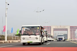 Các xe trung chuyển (xe điện) chở khách du lịch xuất cảnh đi qua vạch phân quảng cầu Bắc Luân 2. (Ảnh: Thanh Vân/TTXVN)